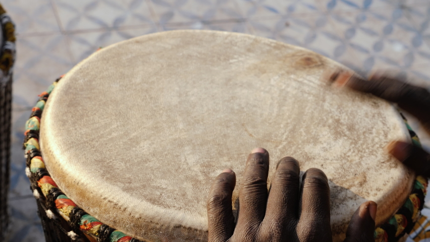 A Senegalese man plays a traditional djembe drum. West-african traditional music, often played in the streets and on festivals. Royalty-Free Stock Footage #1080489332