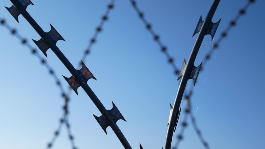 Barbed wire against the blue sky. State border, fight against illegal immigrants Royalty-Free Stock Footage #1080499718