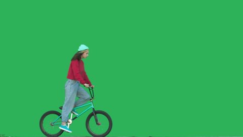 biker girl riding bmx bicycle over green background. Sporty young woman rider have fun with bike. 4k raw video footage