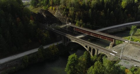 Stone and iron railway bridge by dangerous part of Trans Siberian railways near river in forest mountains. Aerial drone wide view at summer sunny day