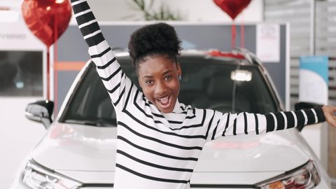 Attractive young woman is getting new car at car dealership