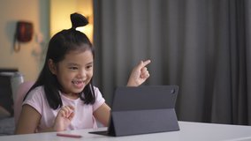 Asian child smile laugh to doing gestures on computer tablet or kid girl student enjoy active and speaking on video call learning to studying online class or person learn from home school in bedroom