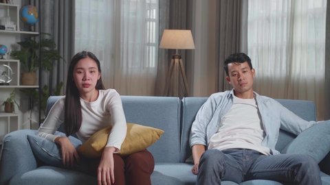 Young Asian Couple Are Watching Tv At Home With Sad Faces. Human Emotions And Television Concept
