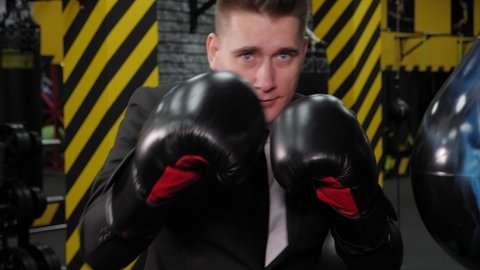 Close-up of a successful serious businessman in boxing gloves, boxing in the ring after a long working day.