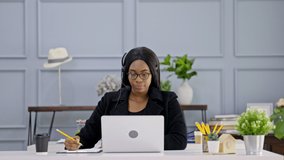 African American Businesswoman with headset to video call with computer meeting at Home. webinar with colleagues. using video conference app video call virtual communication. entertainment online