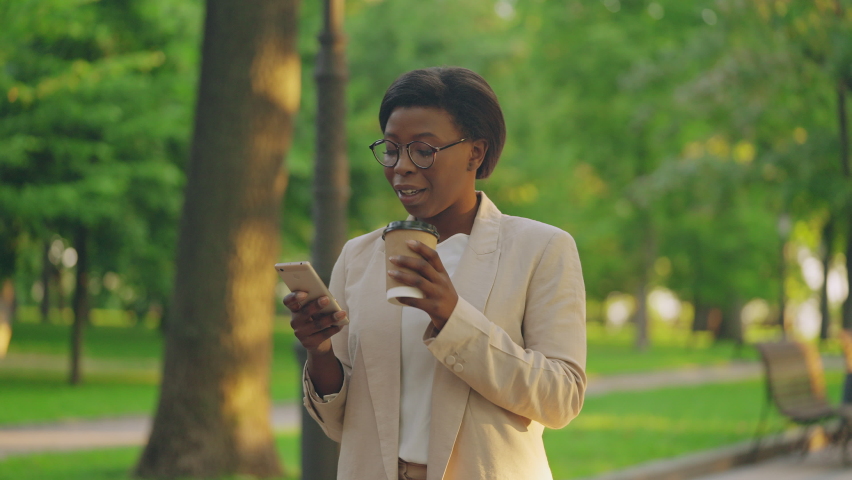 Professional financial analyst typing message on smartphone, drinking coffee