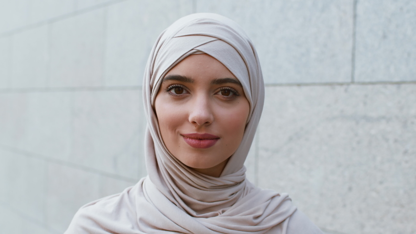 Middle eastern beauty. Close up outdoors portrait of carefree calm young muslim woman wearing hijab smiling to camera, posing outdoors, tracking shot, slow motion | Shutterstock HD Video #1080528485