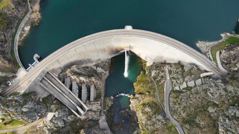 Aerial view drone shot above water dam. Top down shot over a water reservoir with Asphalt road bridge above hydroelectric renewable power plant. High quality 4k footage