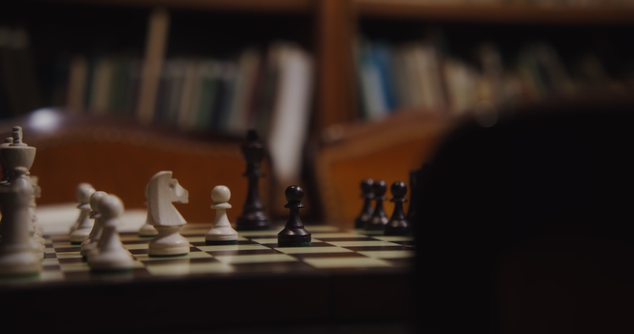 A man of European appearance, dressed in a business suit, plays chess. Close-up of rearranging chess pieces