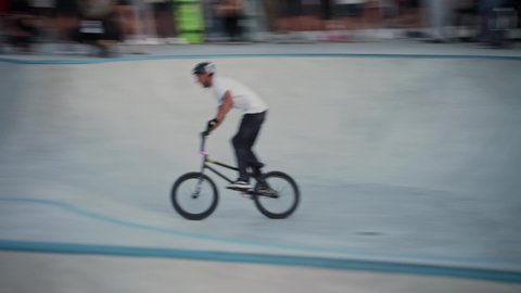 Kyiv, Ukraine - Sept.12.2021.Extreme BMX biker is performing tricks in the skatepark. Backflip. Extreme sport. Crowded skatepark. Group of teenagers shows tricks on the ramp. Bicycle stunts. Bmx rider