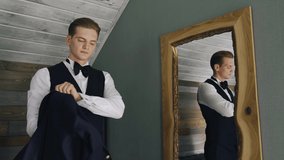 A man puts on a suit standing in front of a mirror going to a meeting. A stylish guy