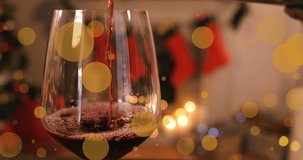 Animation of glowing spots over glass of red wine and christmas decorations. christmas, tradition and celebration concept digitally generated video.