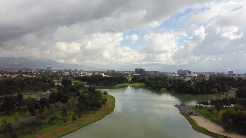 Dolly in shot over a lake in Simon Bolivar Park. Bogota City in the background.