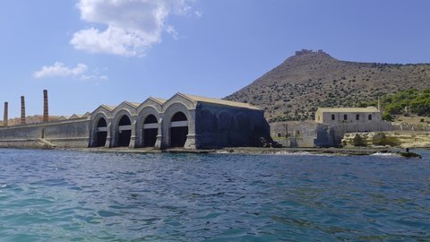 Florio tuna factory or tonnara at Favignana island from boat with Santa Caterina mount and castle in background, Italy. Slow-motion