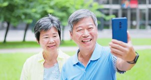 Authentic shot of asian elderly couple have video chat by mobile phone happily outdoor