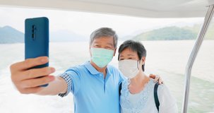 Authentic shot of asian elderly couple wearing face mask have video chat by mobile phone happily on boat in close up
