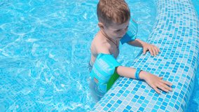 Happy child playing in swimming pool. Summer. Young boy kid child is splashing in swimming pool and having fun leisure activity on open air. Joyful kid in a swimming pool. Little boy at swimming pool.