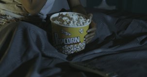 Sleepless african american woman watching TV and eating popcorn at night