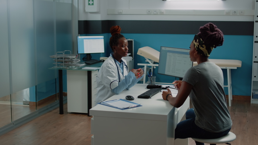 Woman working as doctor talking to patient about sickness in doctors office. Ill person receiving medical consultation and treatment against pain from medic in cabinet for checkup. Royalty-Free Stock Footage #1080559559
