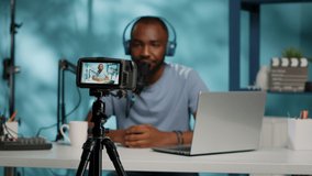 Close up of content creator recording video on camera using modern equipment and tripod. Vlogger with microphone and headphones filming for vlog channel. Man using gadget to film