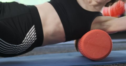 Young woman kneads her shoulder blade and back muscles with a myofascial release roller. Fitness trainer shows relaxation exercises. High quality 4k footage

