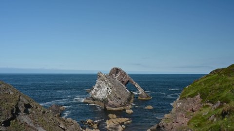 Real time footage of Bow Fiddle Rock with sea movement. This is famous rock formation on the Moray Coast, Scottish Highlands, Scotland. Sunny day with blue sky, no people.