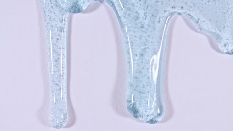 Transparent liquid gel cream with micro Bubbles as it slowly slides down. Macro Shot