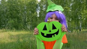 Child girl in a witch costume with jack the pumpkin jumps on Halloween scares everyone
