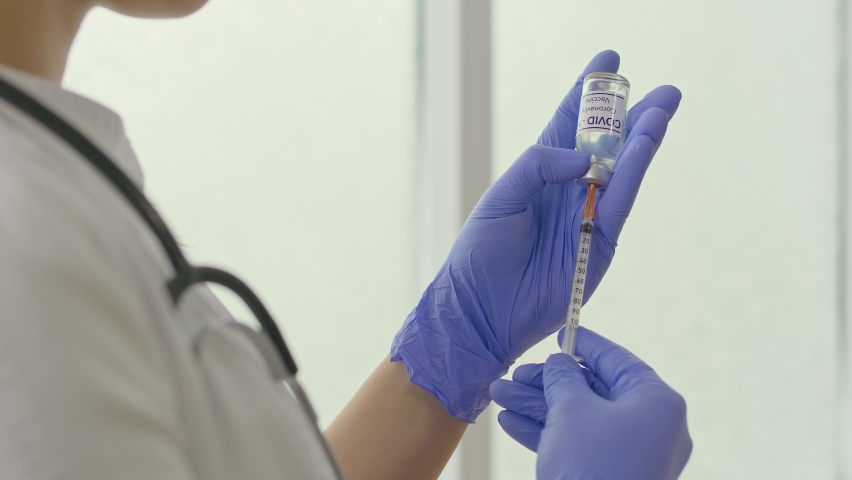 Close-up. A Vial of the COVID-19 Coronavirus Vaccine is Being Used By a Scientist, a Doctor with an Injection Needle.
