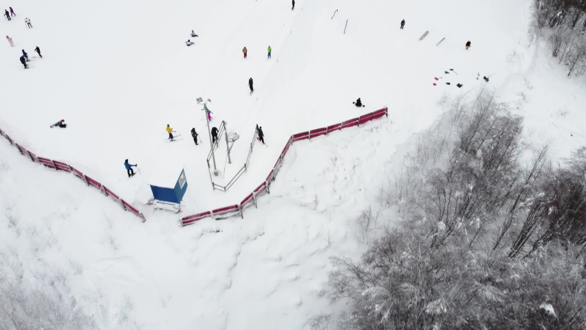 Panoramic top view from drone on cable way in ski resort. Ski lift elevator transporting skiers and snowboarders on snowy winter slope at mountain resort, many people. UHD 4k video | Shutterstock HD Video #1080571358