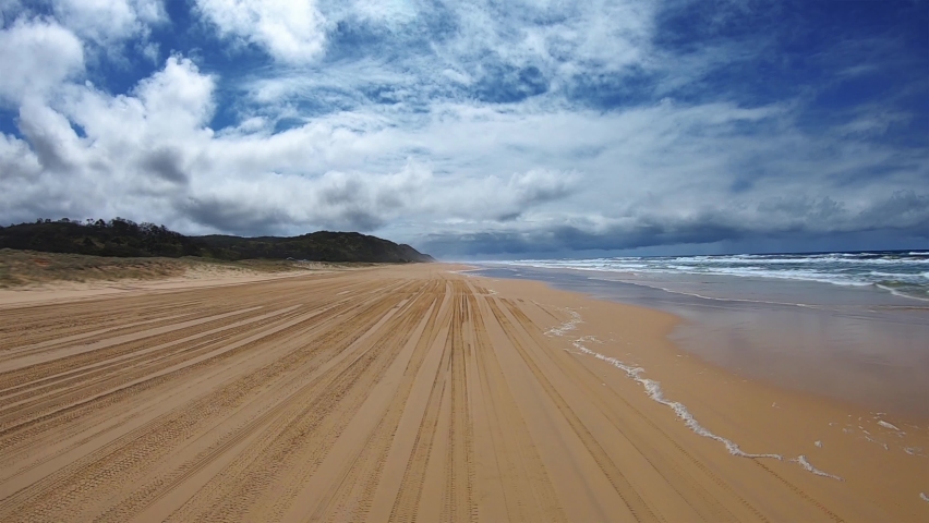 Rear facing driving point of view POV of a deserted Queensland beach under a blue sky with white cloud banks - ideal for interior car scene green screen replacement Royalty-Free Stock Footage #1080572801