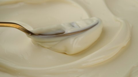 Mayonnaise sauce with golden spoon. Sour cream with spoon, fresh greek yogurt close up. 4K UHD video