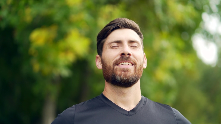 Close up portrait young happy bearded man standing in nature between forest trees relaxes, breathes fresh air closing his eyes. Male enjoys a life of peace calm, quiet in the park. Outdoors. Happiness Royalty-Free Stock Footage #1080574361