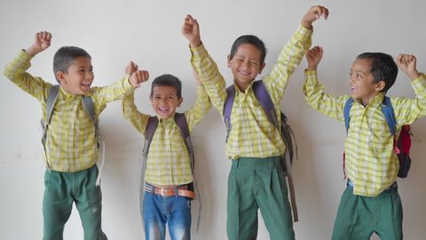 shot of a group of adorable primary school children wearing uniforms with backpacks jumping joyfully and looking happy against a white background or wall. learning and education concept