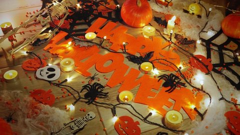 Scary halloween decorations. Halloween party with bats, ghost and skull. Halloween greetings. Trick or treat. Pumpkins with candles on table at night