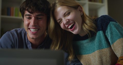 Cinematic shot of young happy couple making video technology call to friends or family with tablet to show new house they bought in living room at home. Concept: technology, family, connection, estate