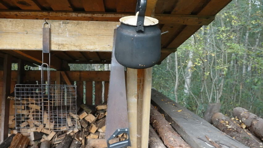 The hanging kettle and saw on the side of the dirty kitchen of the campsite in the middle of the forest in Estonia