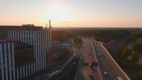 Helsinki.Finland-August 30.2021: Beautiful aerial shot of a highway in Helsinki Finland. Cars driving on the road. Sunset in the background. Drone slowly moving backwards.