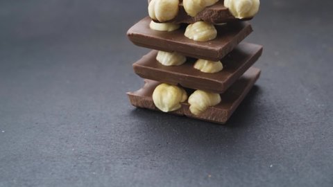 Chocolate tower with hazelnuts. Pieces of chocolate with hazelnuts on a black background. recipe for making chocolate with nuts