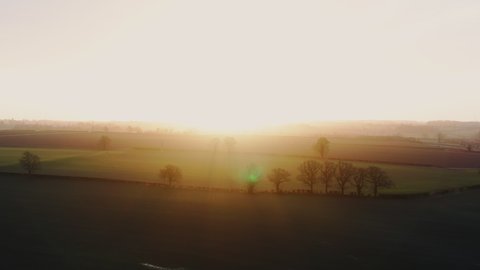 Beautiful morning aerial sunrise in the rural english countryside showing epic landscape farmers harvest wheat fields