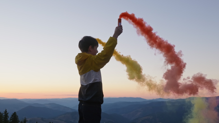 Travel concept. Happy boy tourist stands with burning fires on  background of mountains peaks in autumn at sunset slow motion. Relax. Tourism. Lifestyle. Freedom. Childhood