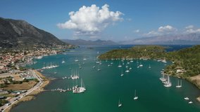 Aerial drone rotational video of iconic port of Nidri or Nydri a safe harbour for sail boats and famous for trips to Meganisi, Skorpios and other Ionian islands, Lefkada island, Ionian, Greece