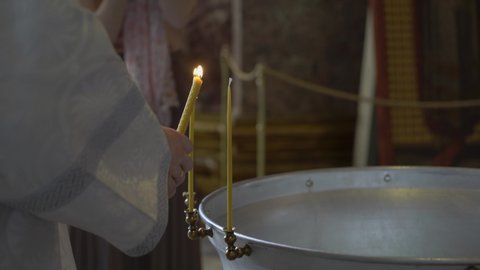 Priest lights candles before the baptism ceremony. Font for christening in the Orthodox Church. Religion - Christianity or Catholicism.
