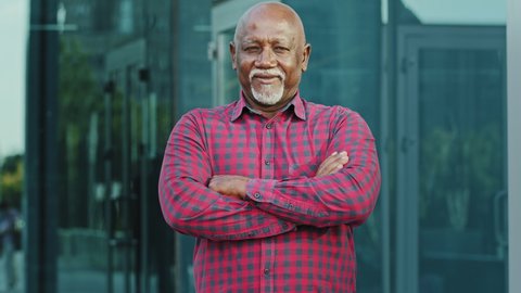 Portrait Elderly African American man with gray beard standing outdoor with arms crossed on chest, nonverbal communication concept, closeup adult person of retirement age showing gesture confidence