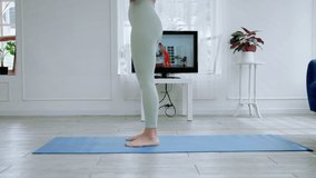 The back of an Asian woman practicing yoga online through TV, health concept.
