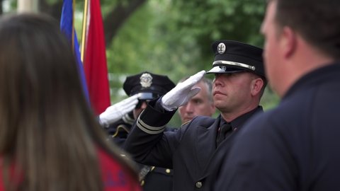 Madison, Wisconsin USA September,11 2021. Firemen and Police Officer saluting American Flag during 911 ceremony.