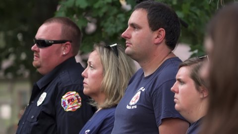 Madison, Wisconsin USA September,11 2021. Firemen and spectators salute the American Flag during 911 ceremony.