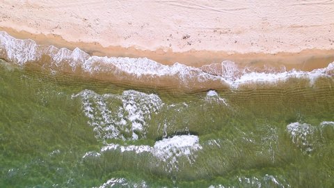 Slow motion overhead drone clip over a beatiful beach with crystal waters and waves crushing on the ground in Keramoti, Kavala,Northern Greece