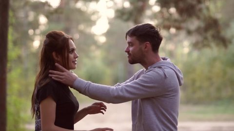 A man pretends to strangle a woman in the evening, standing in the forest. A married couple on a walk. Complex relationships