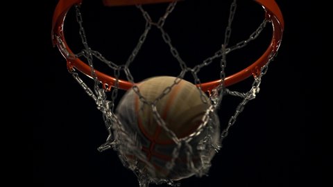 Basketball player scores a goal on the arena. Basketball Court. The decisive moment of the game. Throw the ball into a basketball hoop on the spotlights background.